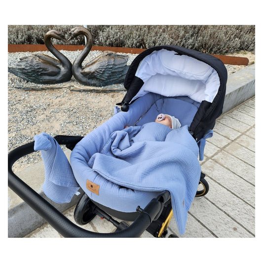 Kinderwagen mit blau Musselin-Babydecke am Strand