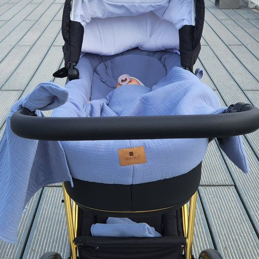 Baby im Kinderwagen mit blauem Musselin Nestchen und Decke