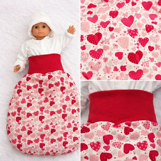 Nahaufnahme des Babyschlafsacks aus Baumwolle mit rotem Herzchenmuster und sichtbarer Stoffstruktu